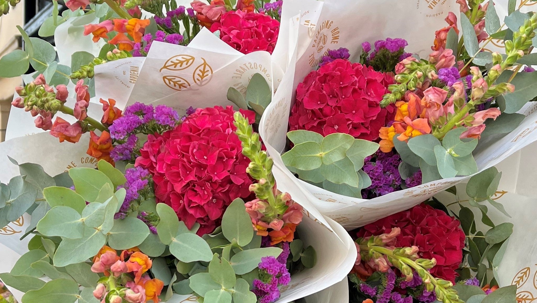 Bouquet of colorful flowers with green leaves in white paper wrapping ready for delivery