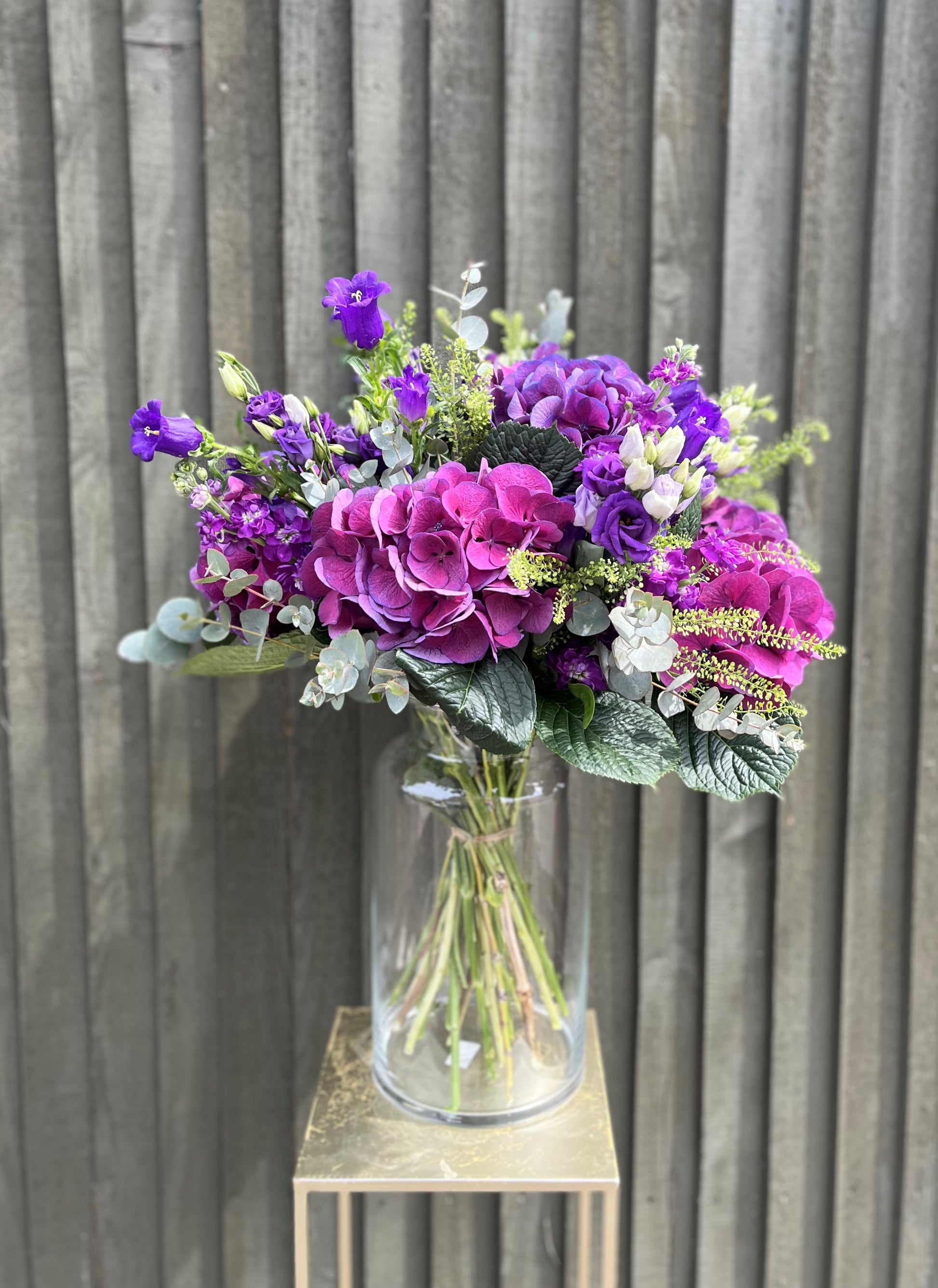 Bouquet of purple and pink flowers in a clear vase against a wooden background