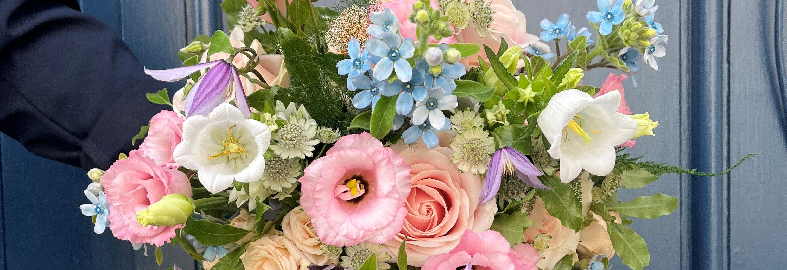 Bouquet of flowers with pink, white, and blue flowers against a blue background