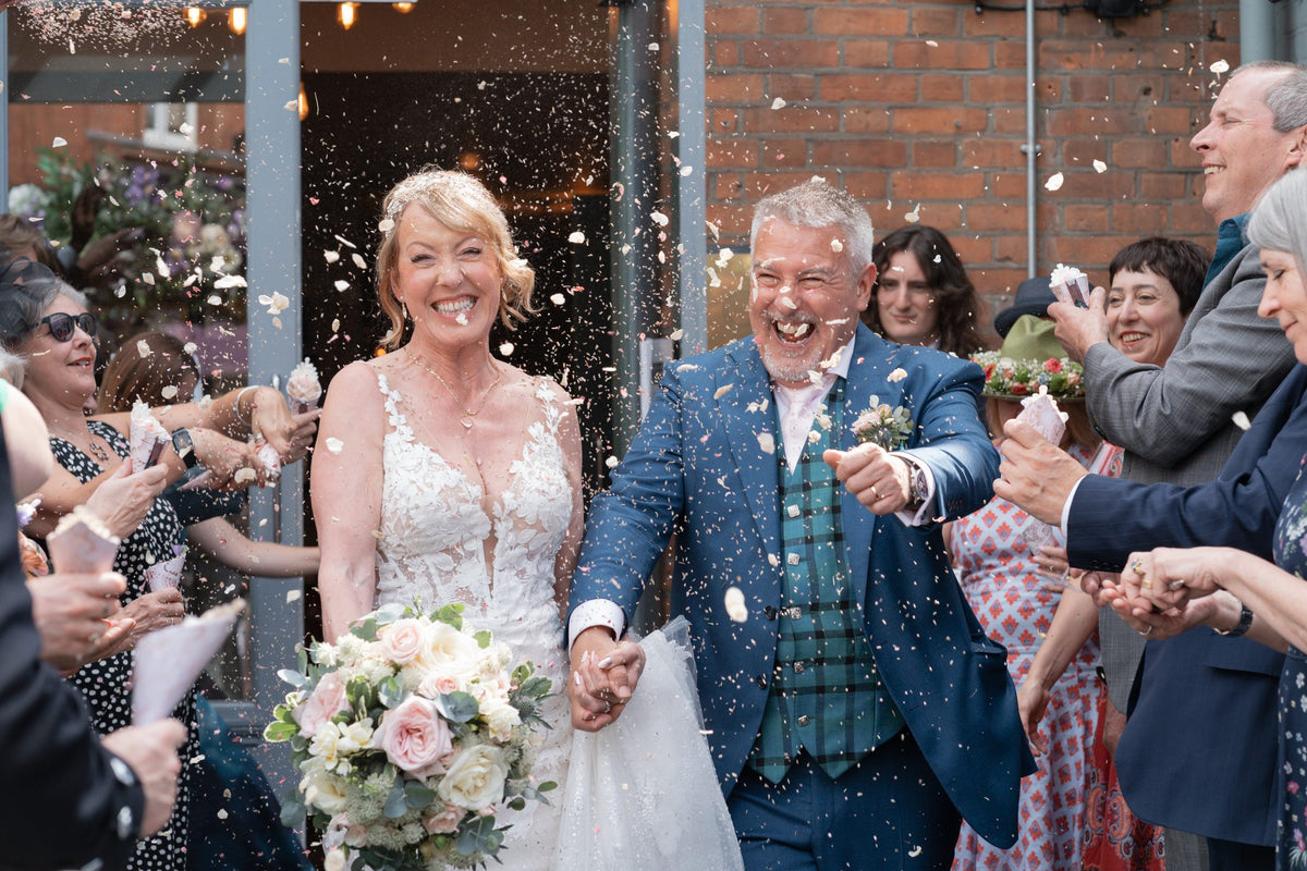 Bride and groom with confetti and a blush wedding bouquet by Gardenia of London